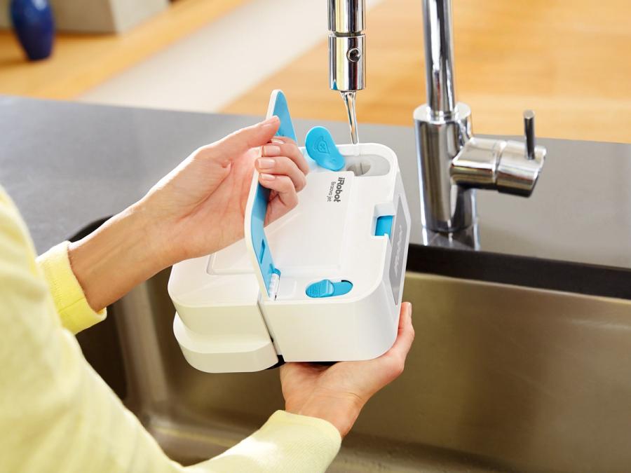 A person holds the robot up to a faucet, and fills it with water.