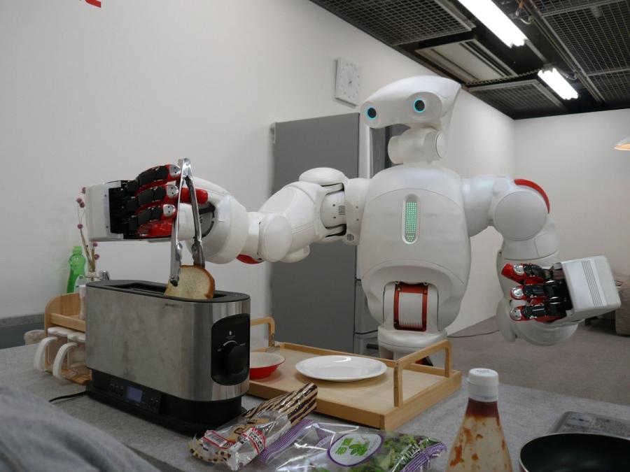 A friendly white humanoid uses a pair of tongs to extract a piece of bread from a toaster.