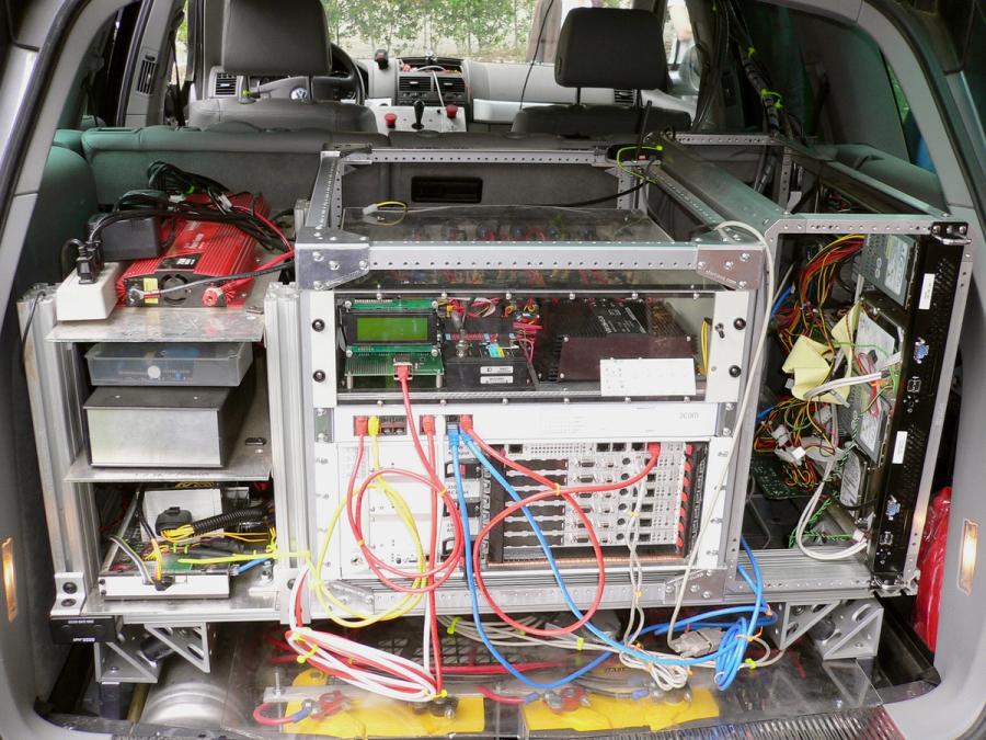 Racks of electronics and servers sit in the trunk of a car.