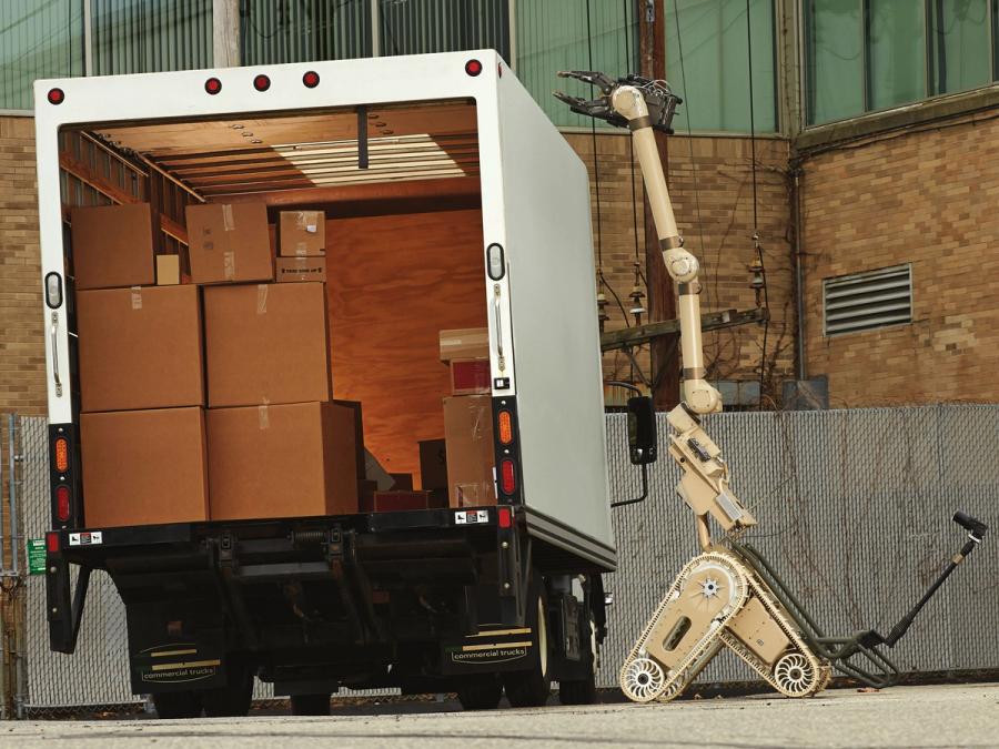 The robot uses it's dual-track system and articulated flippers, as well as it's long articulated arm to reach over the top of a truck.