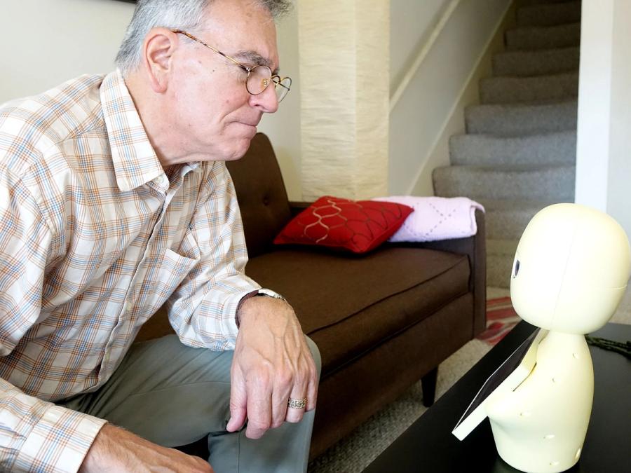 A senior man looks at the robot.