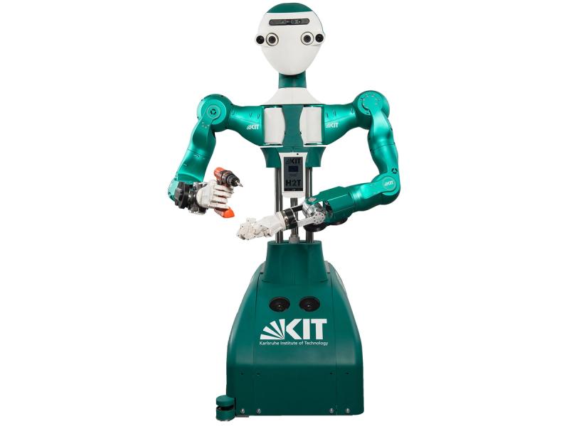 A humanoid robot with a white face and shiny green torso and arms holds an orange drill.