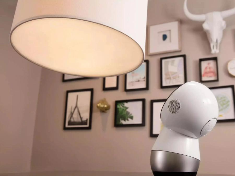 The Jibo robot looks up at a large lamp.