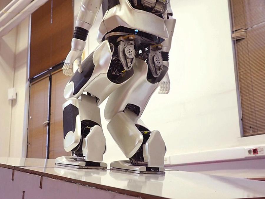 An adult-size humanoid robot walks up a ramp.