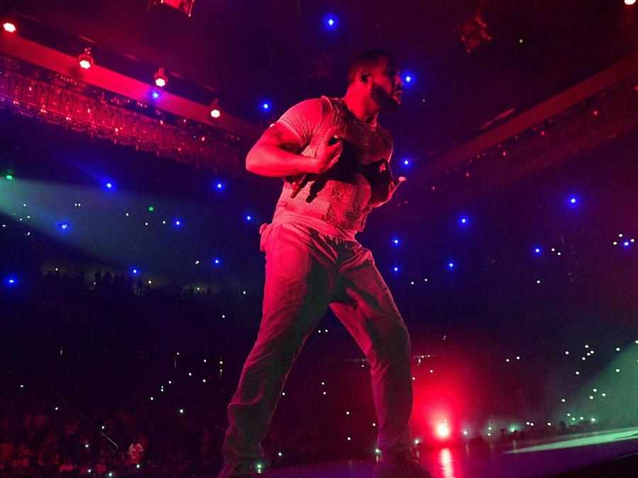 A musician on a colorfully lit stage with small colored dots of light behind him.