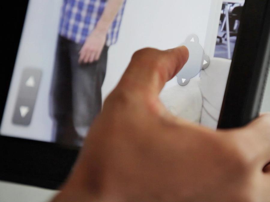 Close up of a finger pressing directional arrows on a tablet.