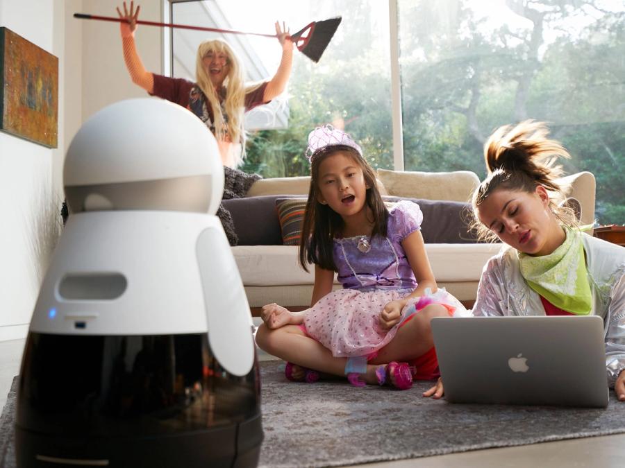 The robot is facing a family of three who wear costumes.