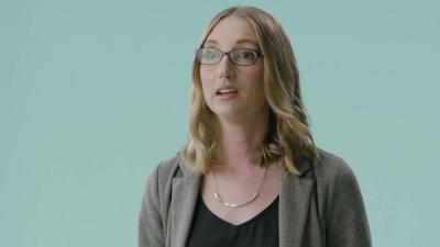 Andrea Thomaz, who wear glasses and has shoulder length brown-blonde hair, looks at the camera in front of a light green background.