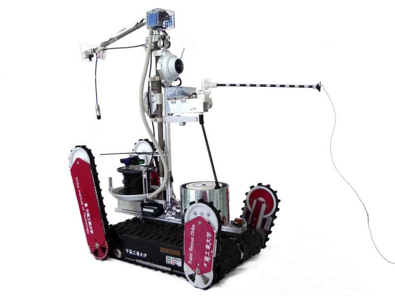 A mobile robot with a black base and four rotating tracked flipper wheels. The base holds electronics, and a single arm extends upwards and holds camera and other equipment.