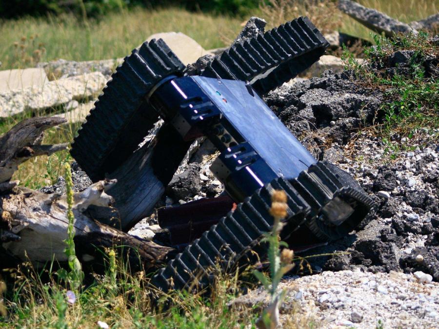 The robot crawls at an angle amid rough rocks.