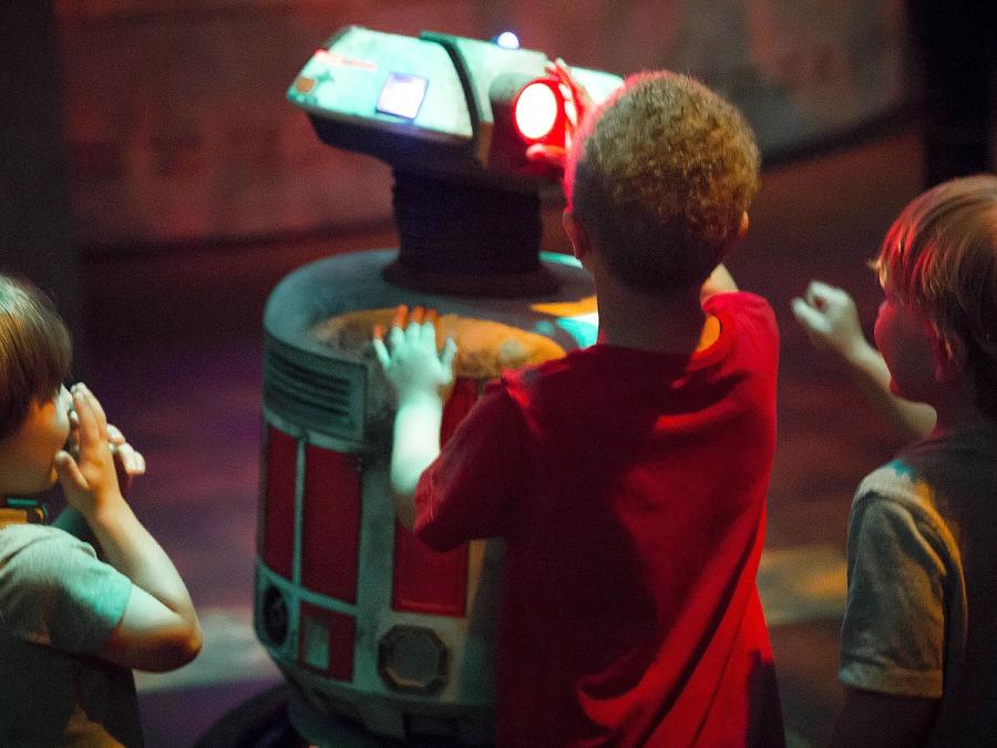 Three children gather around a robot.