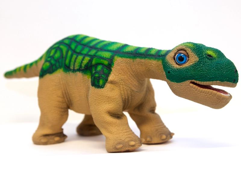 A friendly green and brown baby Camarasaurus dinosaur robot.