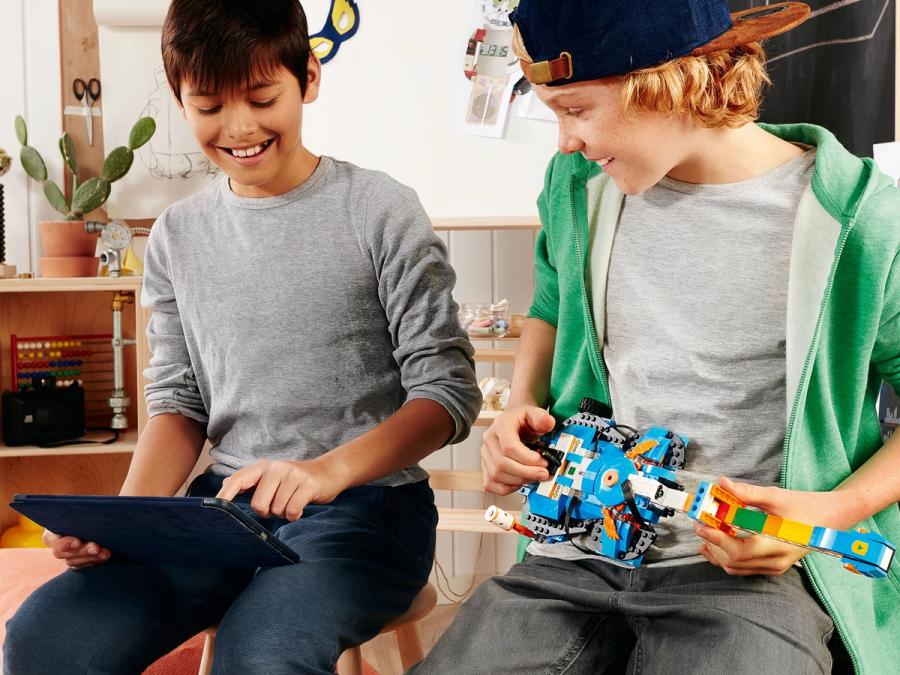 Two teenagers play with a guitar made of Lego bricks.