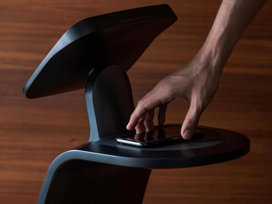 A rear view of a telepresence robot showing a platform that a person holds a phone up to.