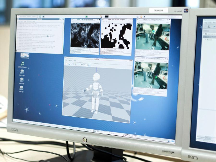 A monitor shows multiple screens with views of what iCub sees and how it is behaving.