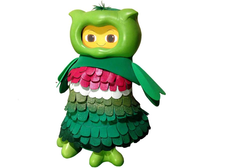 A 30 cm cartoonish robot with a green shell and feather like outfit that gives it the appearance of an owl with a smiling yellow face.