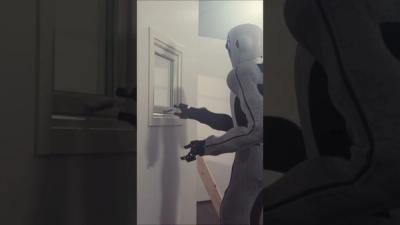 EVE, a gray humanoid robot, uses its hand gripper to open a window.