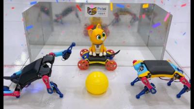 Two small plastic robot dogs stand in front of a yellow plastic ball while a cat figurine sits on a wheeled robot.